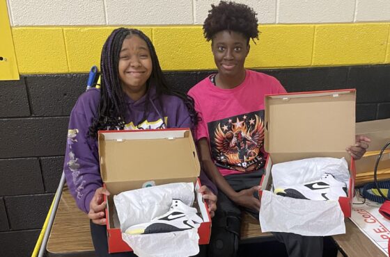 two young female athletes showing open boxes of Nike basketball shoes