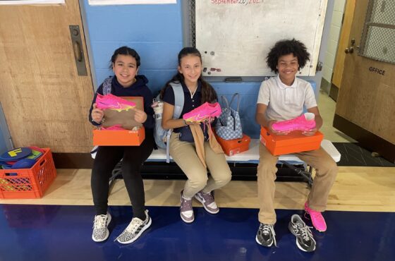 Young students holding pink Nike soccer cleats